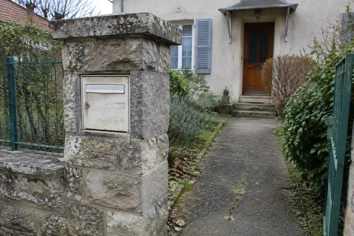 Boîte aux lettres encastrée dans un pilier de clôture en pierre, à hauteur de main